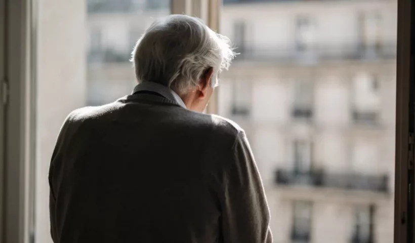 Homme âgé de dos regardant par la fenêtre