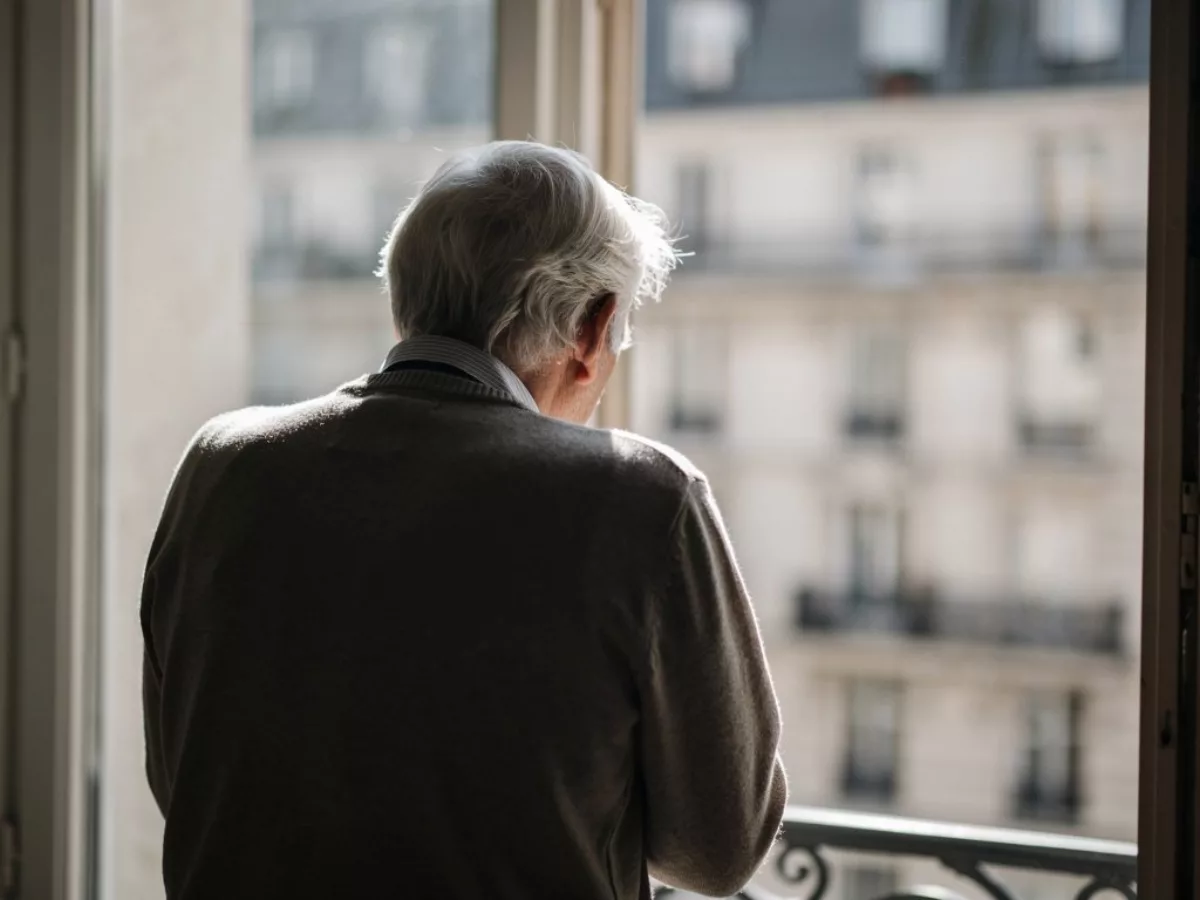 Homme âgé de dos regardant par la fenêtre