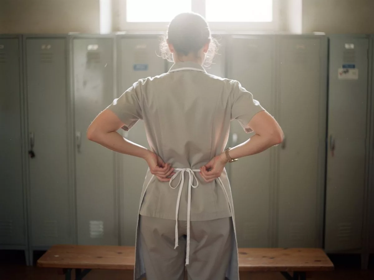 Soignante de dos nouant sa blouse au vestiaire
